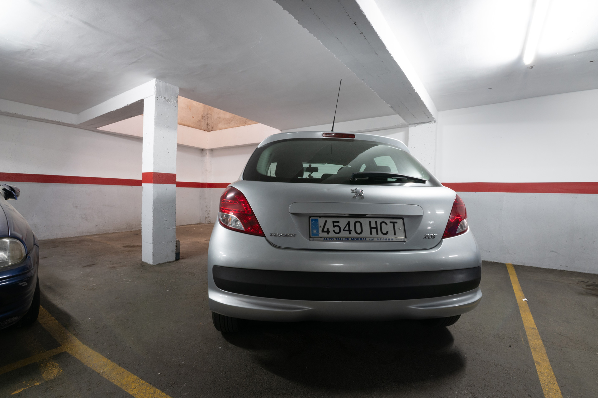 Fotografía inmobiliaria sin edición de garaje subterráneo con coche estacionado, mostrando el tamaño real del espacio y las condiciones del lugar.